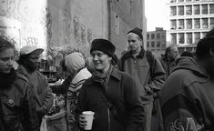 a group of people standing around each other in the middle of a street with graffiti on the walls