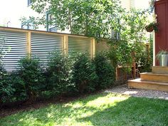 a fenced in yard with grass and bushes next to the stairs leading up to it