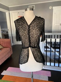 "1930's sheer black lace short sleeve blouse with a high low hem. Black covered buttons up the front. In largely good condition, but does have two holes in the lace, one at the waist and a large hole in the right shoulder. See all photos Womens small 34\" bust 28\" waist 17\" shoulder to waist seam 15\" back waist to the back hem" Fitted Short Sleeve Top With Delicate Lace, Fitted Tops With Delicate Lace And Short Sleeves, Summer Fitted Blouse With Scalloped Lace, Fitted Scalloped Lace Short Sleeve Top, Fitted Sheer Lace Top With Short Sleeves, Sheer Lace Short Sleeve Top, Fitted Lace Top With Short Sleeves, Black Lace Short Sleeve Tops, Elegant Sheer Short Sleeve Lace Top