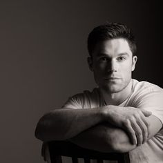 a black and white photo of a man sitting in a chair with his arms crossed