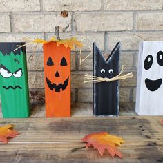 three wooden blocks decorated with pumpkins, jack - o - lantern and ghost faces