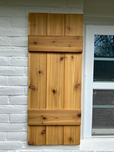 an open window with wooden shutters on the side of a white brick building,