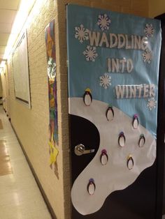 a bulletin board with penguins and snowflakes on it in a hallway next to a door