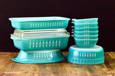 a stack of blue glass dishes sitting on top of a wooden table next to each other