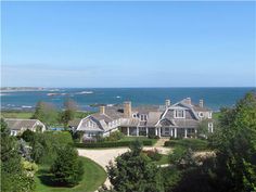 an aerial view of a large house with ocean in the backgroung area