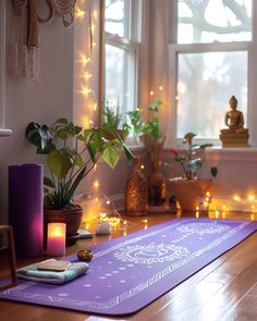 a yoga mat on the floor in front of a window with candles and potted plants