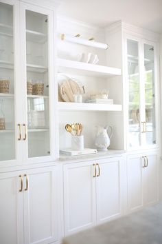 a kitchen with white cabinets and gold handles