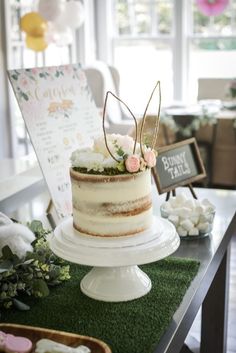 a cake sitting on top of a table covered in green grass next to a sign