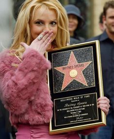 a woman holding up a star on the hollywood walk of fame