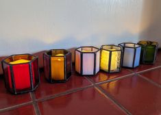 five lit candles sitting on top of a red tile floor