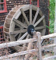 an old wooden wagon wheel on display behind a fence