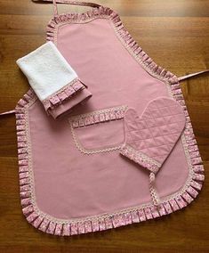 a pink apron and two white towels on a wooden floor