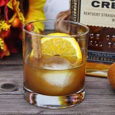 a glass filled with ice and lemon on top of a wooden table