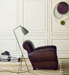 a brown chair sitting in front of a lamp on top of a hard wood floor