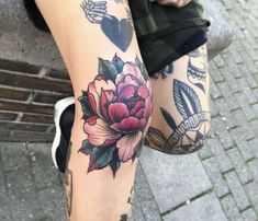 a woman's legs with tattoos on them and flowers in the middle of her leg