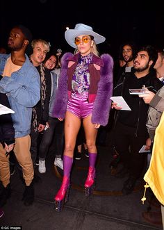 lady in purple outfit and cowboy hat surrounded by people