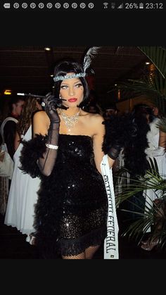 a woman in a black dress and feathered headpiece holding a sign with the words miss america on it