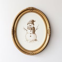 a drawing of a snowman in a gold frame on a white wall behind it