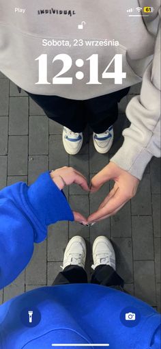 two people standing next to each other making a heart shape with their hands in front of them