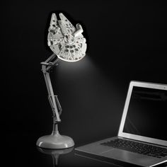 a laptop computer sitting on top of a desk next to a light that is turned on