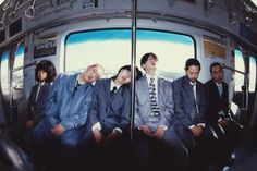 four men in suits are sitting on a bus