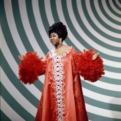 a woman in an orange dress with red feathers