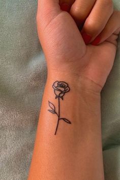 a woman's wrist tattoo with a single rose on the left side of her arm