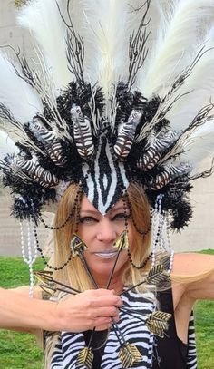 Zulu warrior headdress!! I got inspired from one of my trip to Africa. The Zulu are an African ethnic group of the Bantu  with more then eleven million people and the largest ethnic group in South Africa.  This headdress was showing in Multicultural Fashion show on May 13 in Glendale AZ. Large white and black headdress decorated with wood zebras, white and black branches, white featherlike spiks, siquin, beads. Headband type headdress has elastic in the back fits most head size. Headdress size about 16x25x5 Colors could be slightly different from the picture you see due to your devise setting. Check my shop for other fun crowns. Please contact me for special order. Each crown one of the kind, hand made. I enjoyed making them just as much as you will enjoy to wear.   This item shipped in th Bohemian Crown Headpiece For Carnival, Unique Festival Headpiece With Tall Crown, Unique Tall Crown Headpiece For Festival, Bohemian Crown Costume Hat For Carnival, Bohemian Costume Hat With Structured Crown For Festivals, Bohemian Crown For Carnival, Fantasy Festival Headpiece With High Crown, White Tall Crown Headpieces For Festivals, Bohemian Teardrop Crown For Festivals