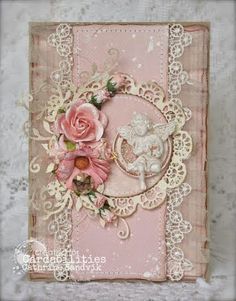 a pink card with an angel and flowers on the front, surrounded by lacy doily