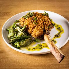 a white plate topped with chicken and broccoli covered in mustard sauce on top of a wooden table