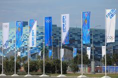 the olympic flags are lined up in front of an office building with blue glass windows