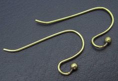 a pair of gold ear hooks on a black surface with one hook in the middle