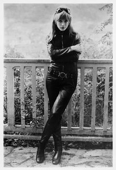 black and white photograph of a woman leaning on a fence with her arms folded over her chest