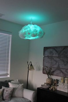 a living room filled with furniture and a green light hanging from the ceiling above it