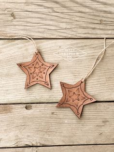 two wooden stars are hanging from string on a wood surface, one is brown and the other is tan