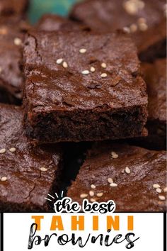 chocolate brownies with sesame seeds are stacked on a blue and green plate, ready to be eaten