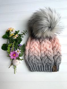 a pink and grey hat next to flowers