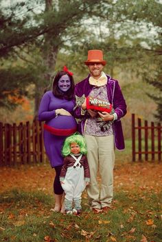 two people dressed up in costumes standing next to each other on grass with trees and fence behind them