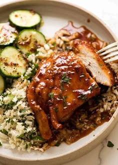 a white plate topped with chicken, rice and cucumbers