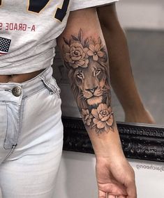 a woman's arm with a lion and flowers tattoo on her left arm, next to a mirror