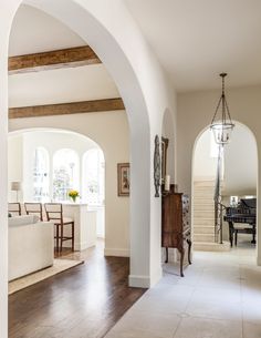 an archway leads to the living room and dining area in this house with white walls, wood flooring and arched doorways