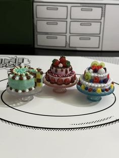 three small cakes sitting on top of a table next to each other in front of drawers