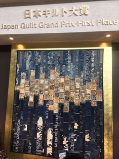 a woman standing in front of a quilt hanging on the wall next to a sign that says japan quilt and pr - first place