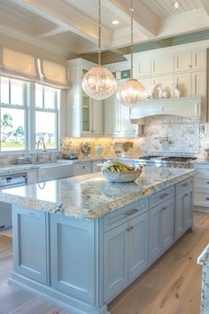 a large kitchen with an island in the middle and two chandeliers hanging from the ceiling