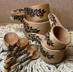 wooden spoons and bowls with black leaves on them sitting on a woven placemat