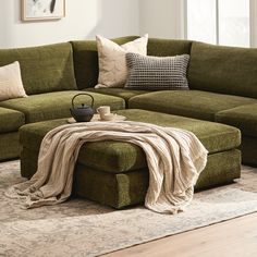 a living room with green couches and pillows on top of the floor, coffee table in front of it