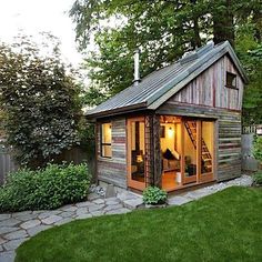 a small wooden shed with windows on the side and stairs leading up to it's door