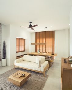 a living room filled with furniture and a ceiling fan in the middle of it's walls