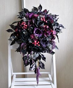 a bridal bouquet sitting on top of a white chair next to a wooden wall