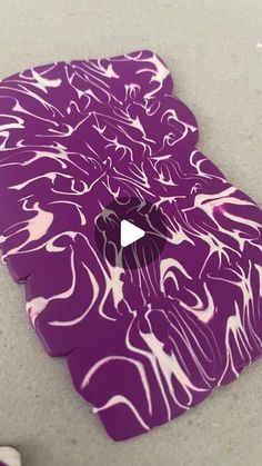 a purple piece of paper with white swirls on it and a video player in the background